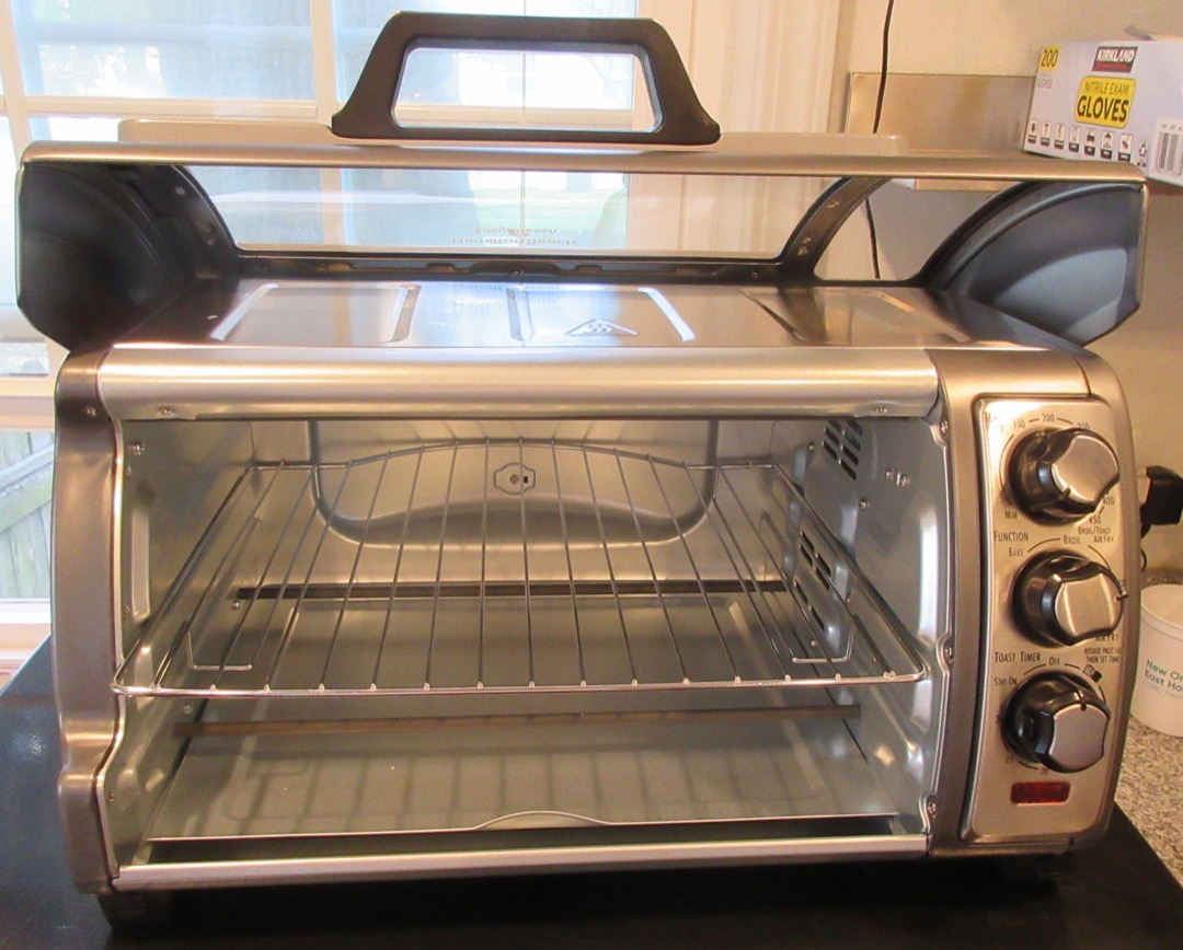A countertop toaster oven with its door open, showing the interior cavity and wire rack