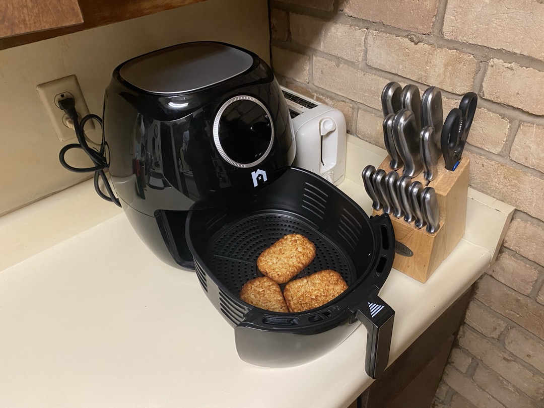 An air fryer on a kitchen counter with its basket pulled out