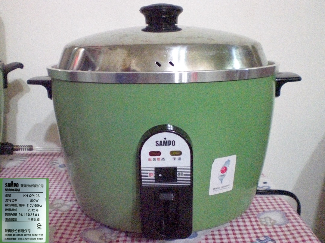 A stainless-lidded Taiwanese-style steam rice cooker with a stainless steel inner pot sitting on a kitchen counter