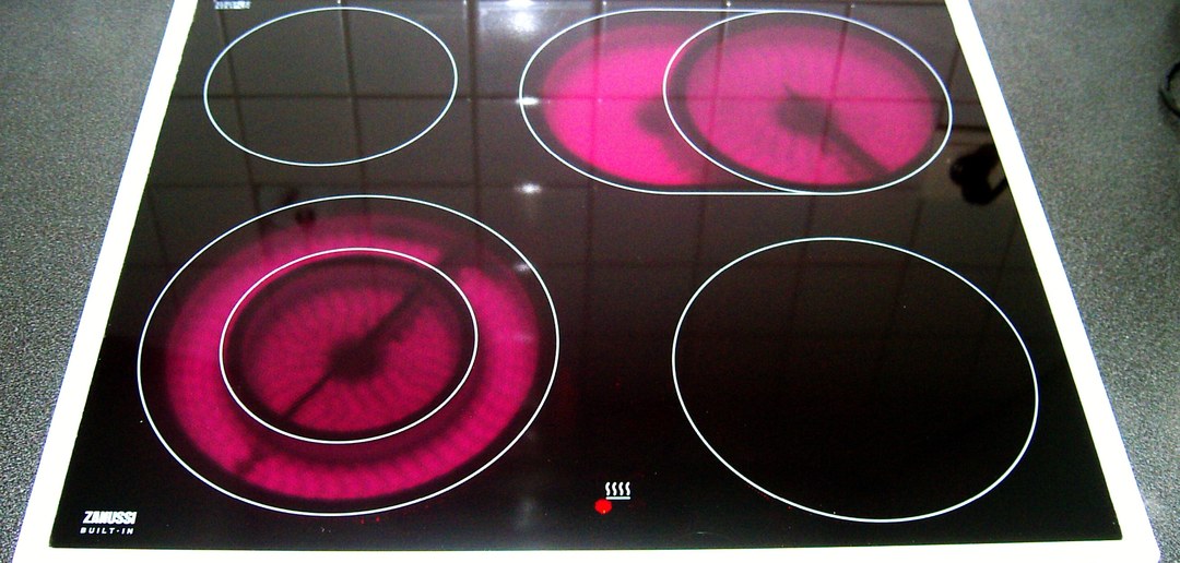 A black ceramic glass cooktop seen from above with two radiant elements glowing red beneath the surface