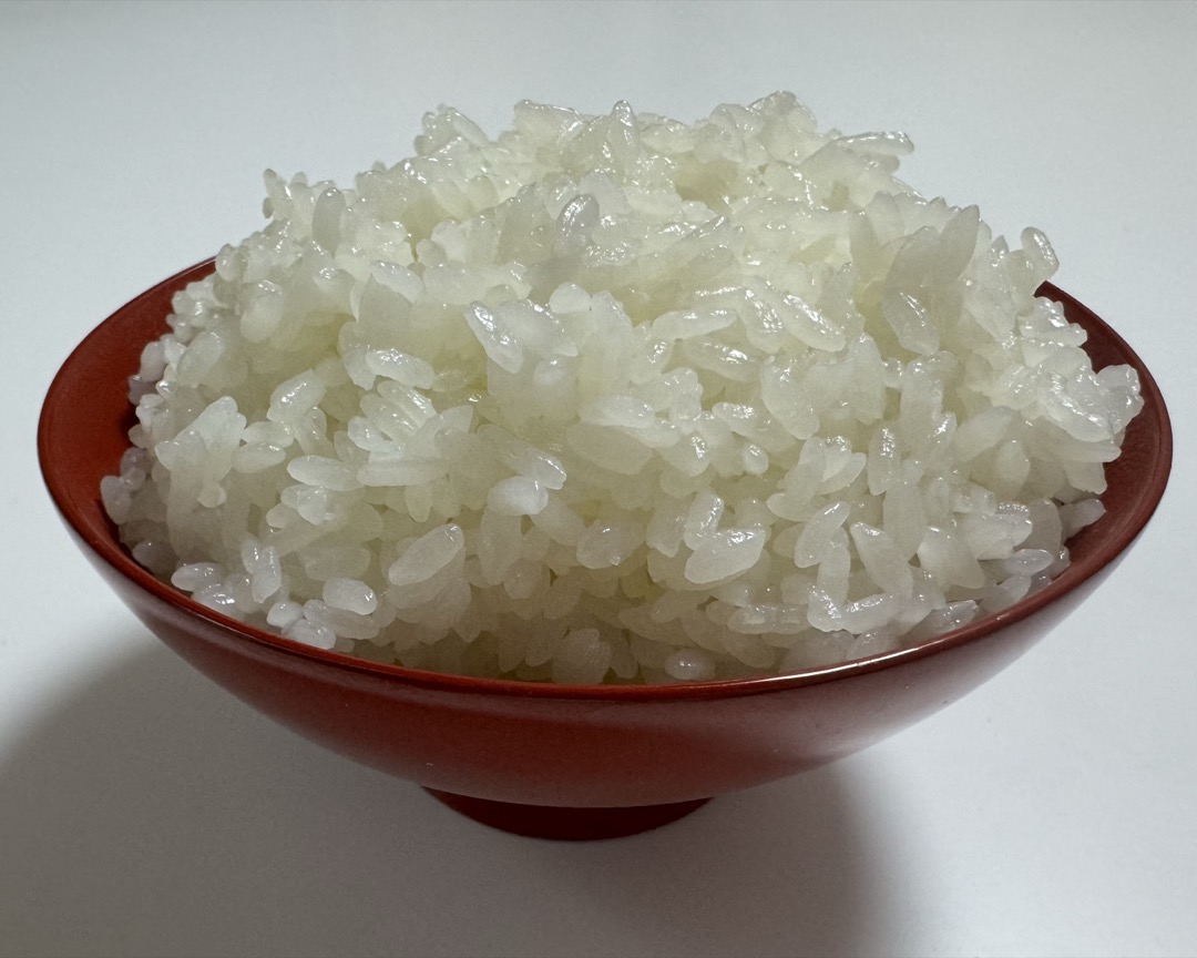 Bowl of glossy cooked Japanese short-grain rice served in a red lacquer rice bowl