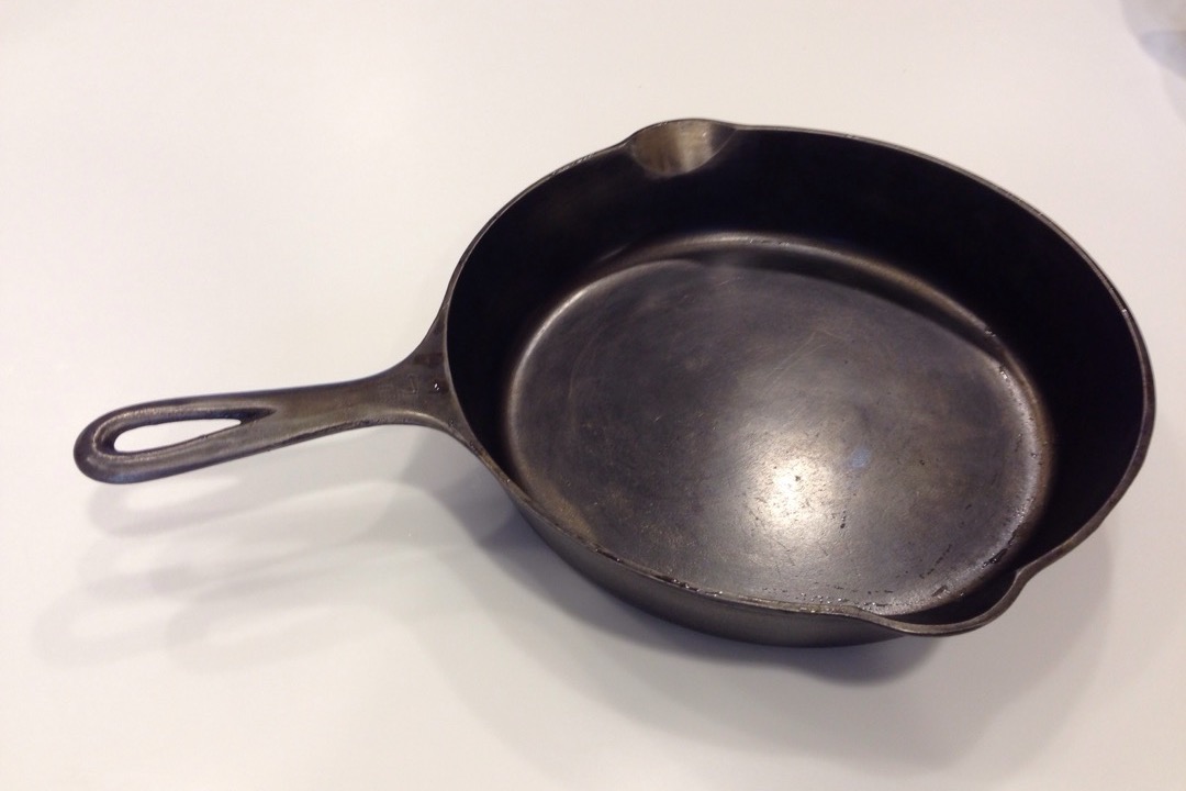 A well-used black cast iron skillet photographed from above on a white surface