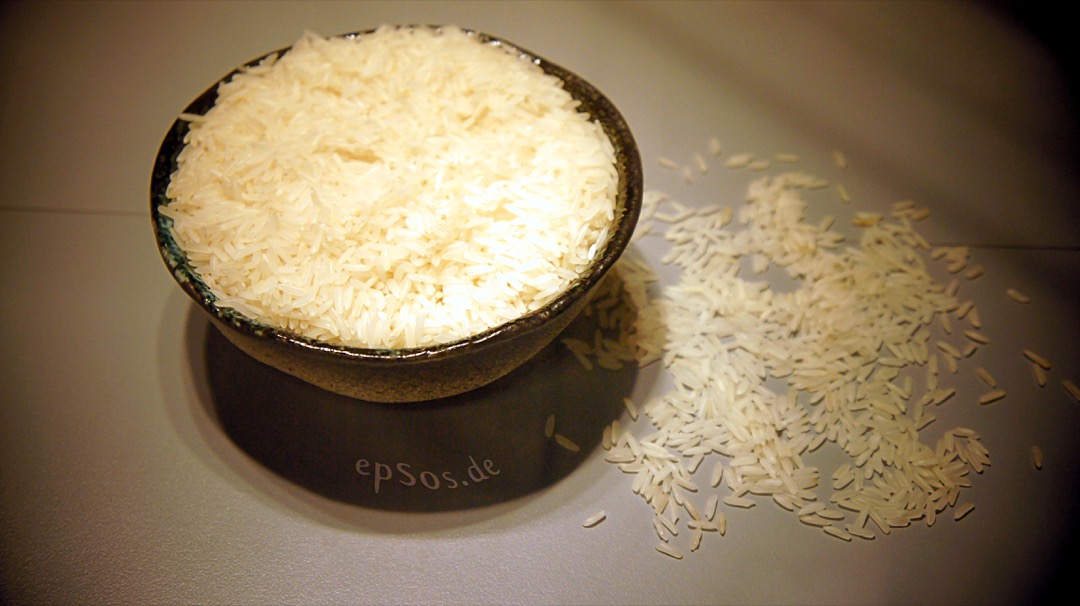 White ceramic bowl filled with cooked white rice on a plain surface