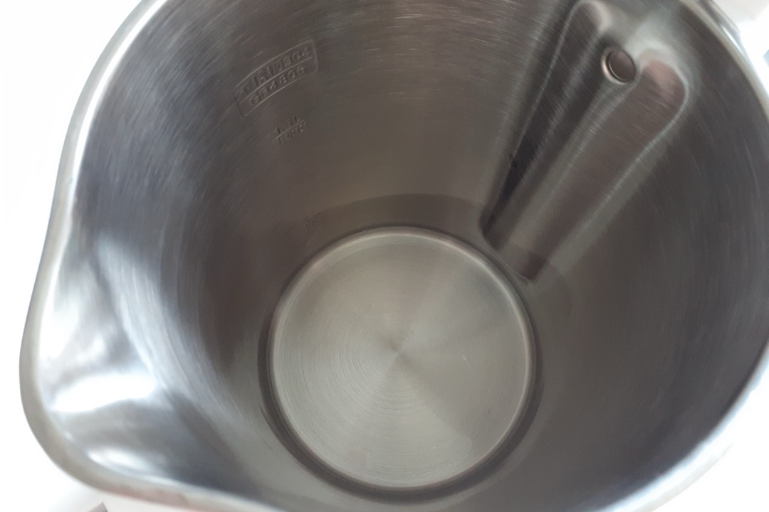 Looking down into the seamless stainless steel interior of an electric kettle, showing the etched grade stamp, the fill marking and the steel heating plate